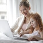 Woman teaching kid on laptop