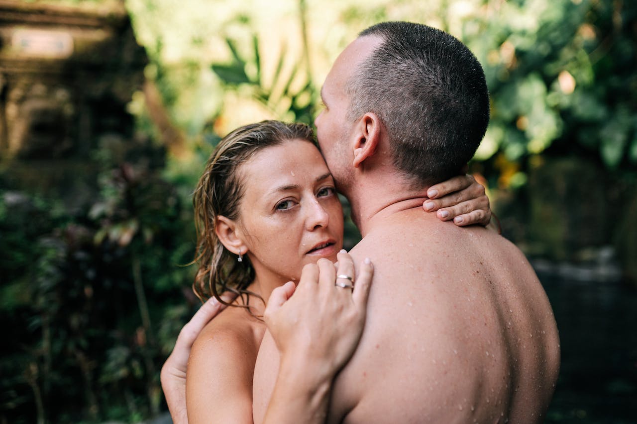 shirtless woman and man hugging in nature