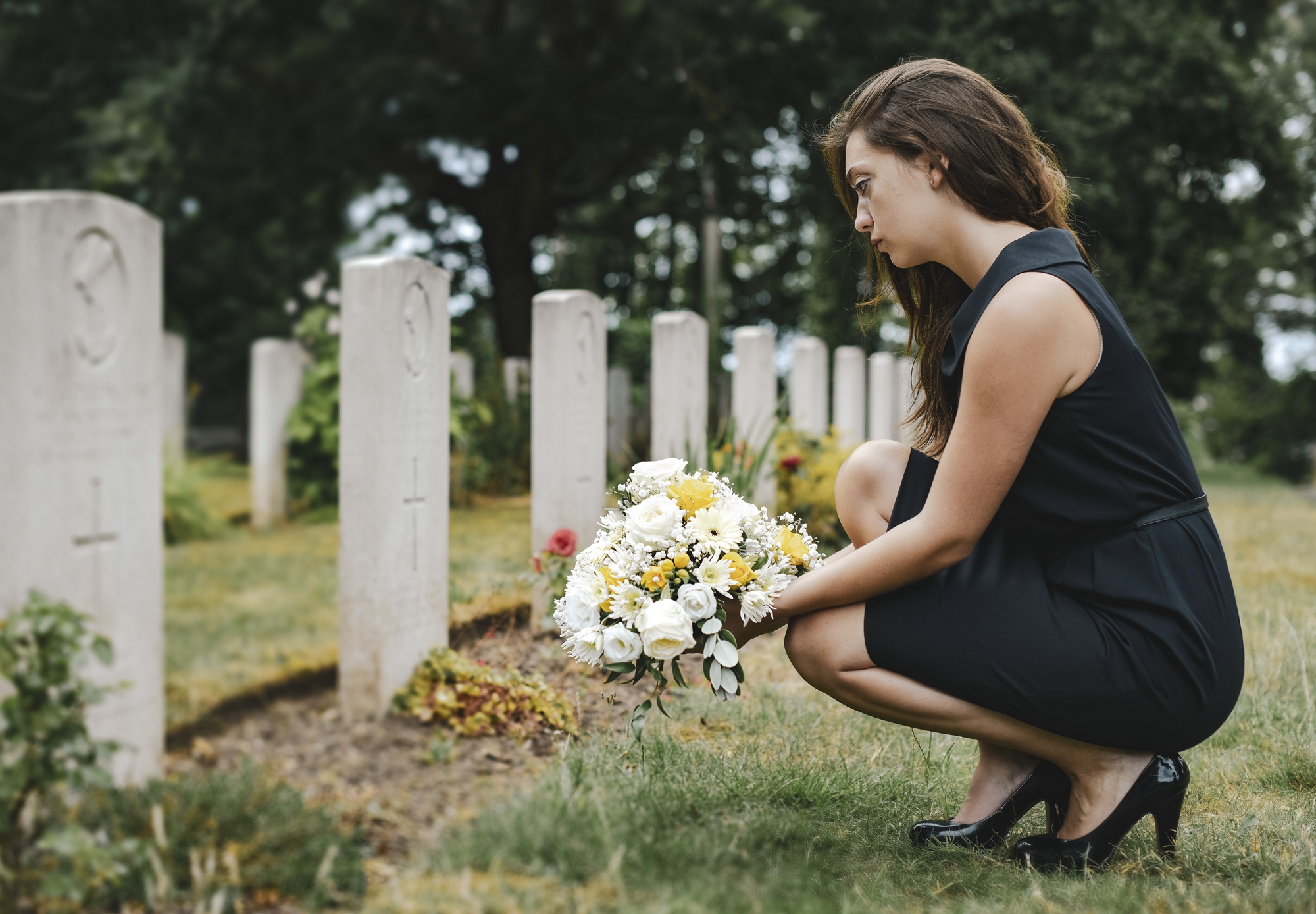 Young woman laying flowers at the grave