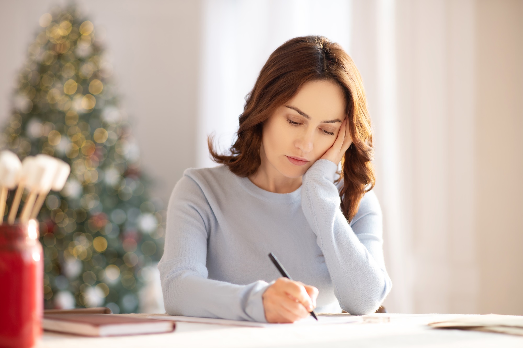 Young woman writing and looking upset and lonely